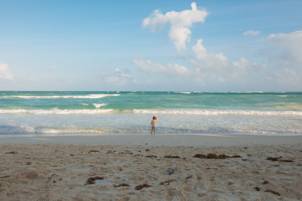 Tochter hält ihren Gips vorm karibischen Meer nach oben