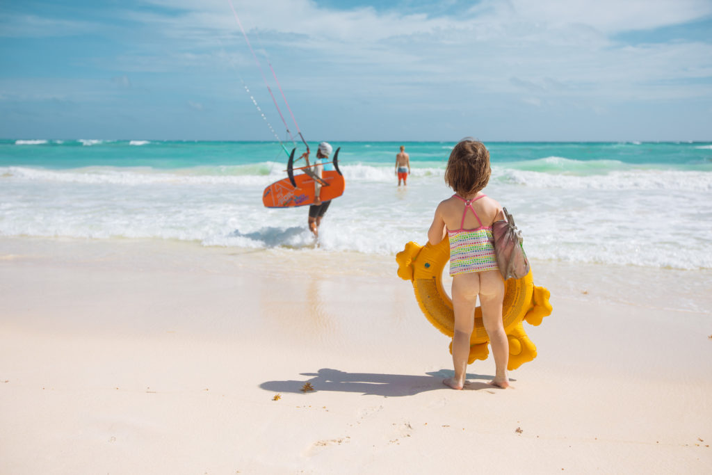 Töchterlein mit Planschkrokodil guckt einem Kitesurfer zu